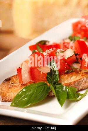 Delicious Bruschetta with tomato, mozzarella and basil with Parmesan cheese in the background Stock Photo
