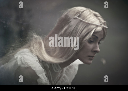 A blonde hair lady with big blue sad eyes looking with sad emotion wearing white dress Stock Photo