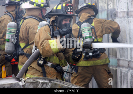 A woman firefighter pouring water on a fire in Wisconsin Stock Photo