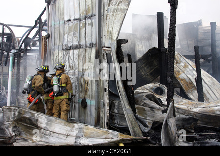Firefighters working on gaining access to a fire in the burning debris Stock Photo