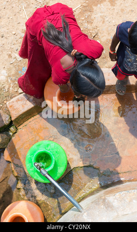 Rural Indian village girl collecting water from a communal water tank. Andhra Pradesh, India Stock Photo