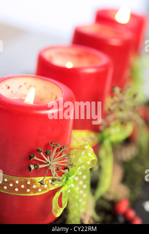 Four burning red Advent candles with green ribbons Stock Photo