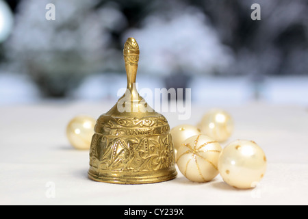 Golden Christmas bell and Christmas balls in front of snow covered terrace Stock Photo