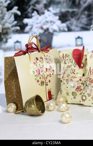 Golden Christmas bell, Christmas balls and gift bag in front of snow covered terrace Stock Photo