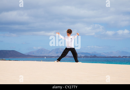 Young attractive woman making Thai-chi movements in the dunes by the ocean Stock Photo