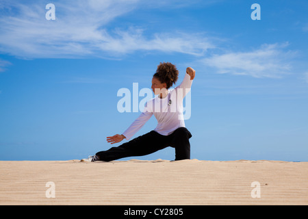 Young attractive woman making Thai-chi movements in the dunes by the ocean Stock Photo