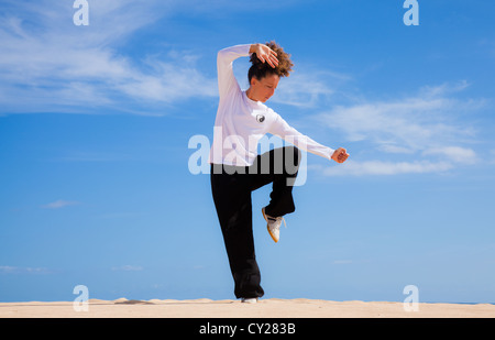 Young attractive woman making Thai-chi movements in the dunes by the ocean Stock Photo