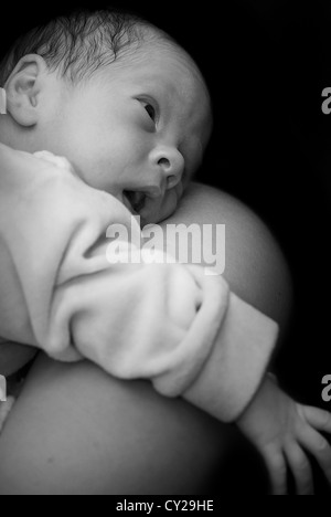 Newborn on mothers shoulder in black and white Stock Photo