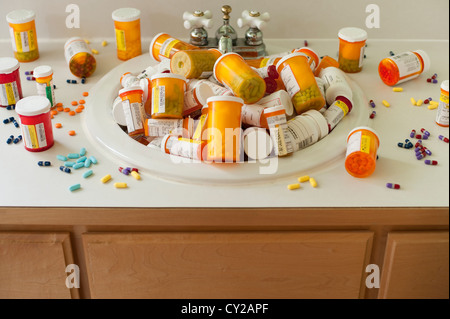 Pills and pill bottles scattered over sink counter and in sink in bathroom Stock Photo