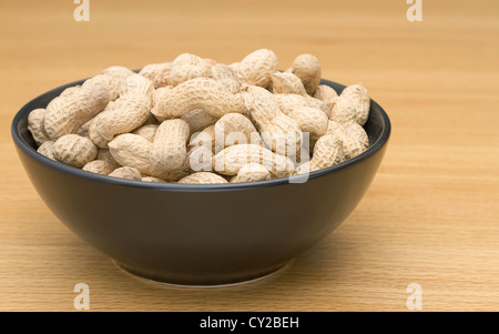 Peanuts in a black bowl on table Stock Photo