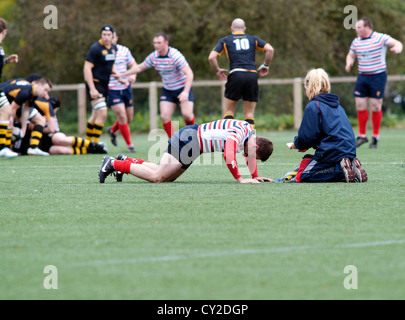 physiotherapist attends to injured rugby player in  match between burnage and birkenhead park Stock Photo