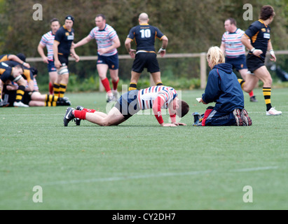 physiotherapist attends to an injured player in  the rugby match between burnage and birkenhead park Stock Photo