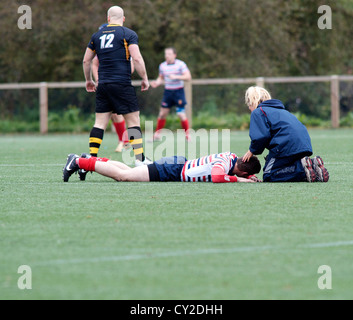 physiotherapist attends to injured player  from a match between burnage and birkenhead park Stock Photo