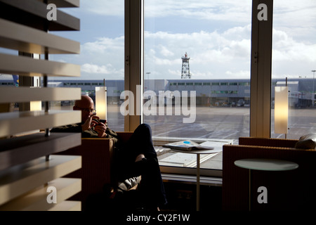 Man waiting and texting in Skyteam Executive Lounge on Terminal Four in Heathrow - London UK Stock Photo
