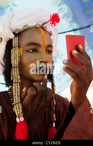 Wodaabe man is putting on make up in preparation for dancing at the gerewol festival in northern Niger, Africa