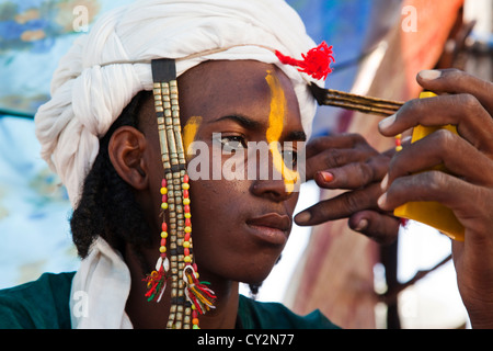Wodaabe man is putting on make up in preparation for dancing in Ingal, Niger