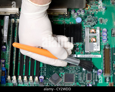 technician brushing dust of mother board Stock Photo