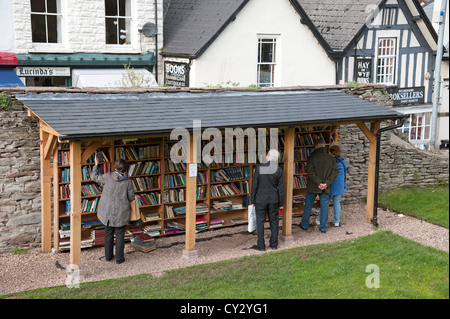 Customers buying secondhand books at Hay on Wye Powys Wales UK  In the background bookselling shops in the town centre Stock Photo
