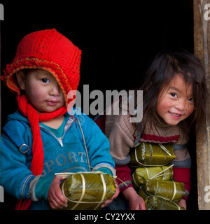 Black Hmong Kids Holding Wrapped Rice Cakes For Tet, Sapa, Vietnam Stock Photo