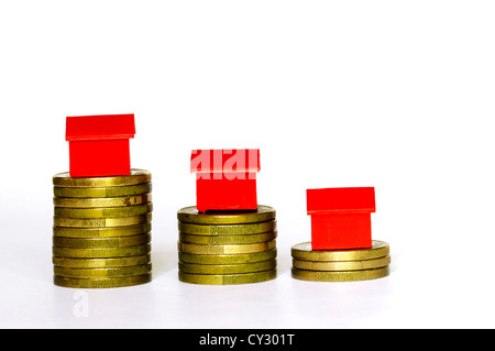 Plastic model houses balanced on top of stacks of coins.