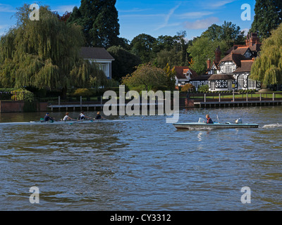 Rowers on the Thames River in Maidenhead, Berkshire. Rowers in a quadruple scull with a coach in a pilot boat observing. Stock Photo