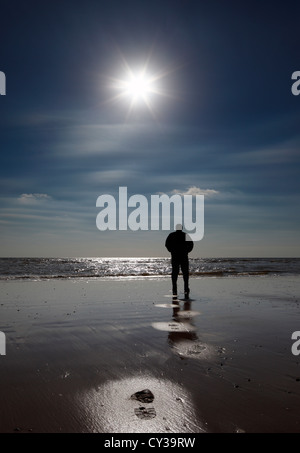 Silhouette of a man walking on a beach.