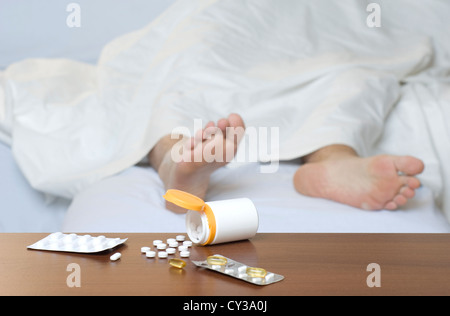 Different types of pills on the table. Person sleeping in the background. Stock Photo