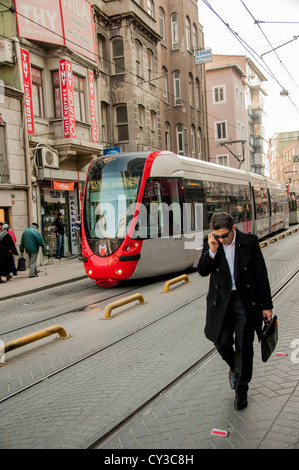 A man on his mobile phone in the Sirkeci district in the old part of Istanbul with T1 tram in the background Stock Photo