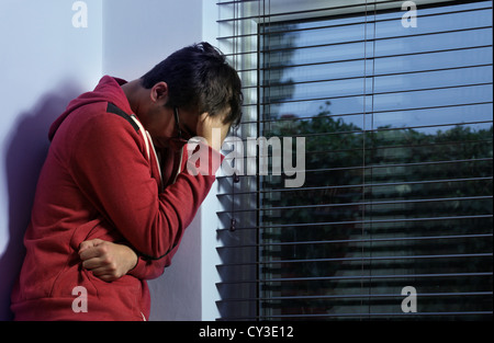 Young man standing by a window hand on head. Stock Photo