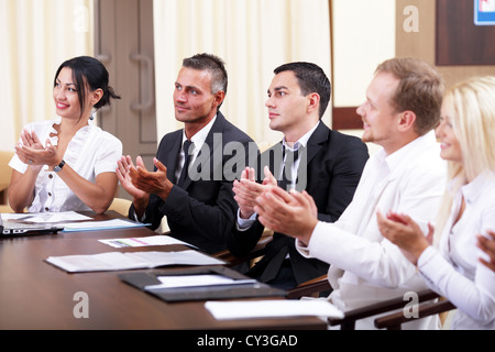 Multi ethnic business group greets you with clapping and smiling Stock Photo