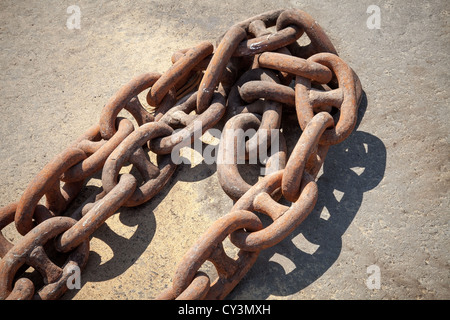Rusty ship anchor chain on dry coast in the port Stock Photo