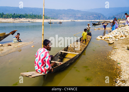 Bangladeshi family on a small boat collecting stones and boulders to be used in construction sites. Jaflang, Sylhet, Bangladesh Stock Photo
