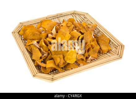 A small wicker basket filled with sweet potato chips and small pieces of dried apple slices on a white background. Stock Photo