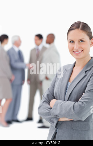 Smiling saleswoman with arms folded and colleagues behind her Stock Photo