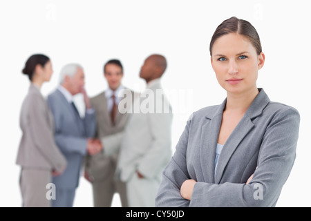 Serious saleswoman with arms folded and colleagues behind her Stock Photo