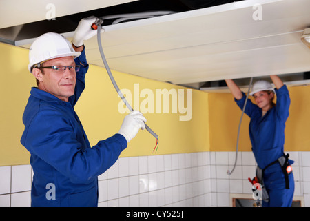 Two electricians working on false ceiling Stock Photo