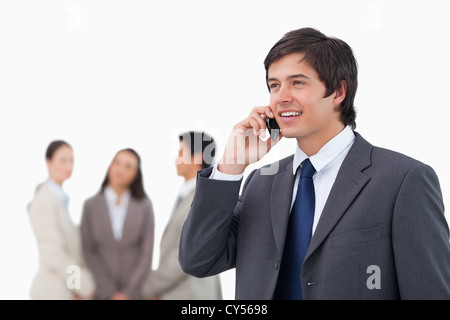 Smiling salesman on his cellphone with colleagues behind him Stock ...