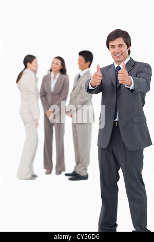 Salesman giving thumbs up with colleagues behind him Stock Photo