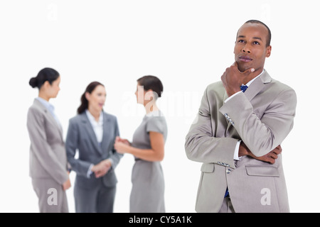 Thoughtful businessman looking up with co-workers behind him Stock Photo