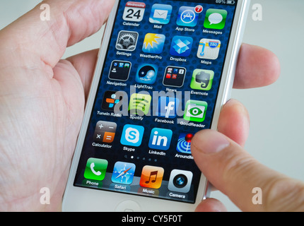 Close-up detail of man holding new iPhone 5 smart phone showing screen with many apps Stock Photo