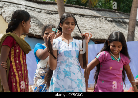 Indian Mother brushing and plaiting daughters hair for Dasara Festival in a rural indian village. Andhra Pradesh, India Stock Photo