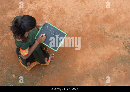 Indian village girl writing english alphabet on a chalkboard in a rural indian village. Andhra Pradesh, India. Copy space Stock Photo