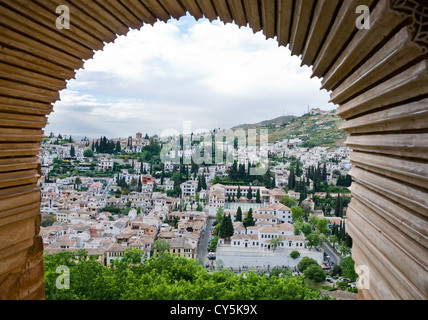An aerial view of white houses of granada andalucia through a arched window from alhambra palace Stock Photo
