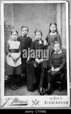 Edwardian Victorian studio portrait of children brothers and sisters. The older child is wearing the Blue Coat School uniform. Birmingham Uk Circa 1900s HOMER SYKES. Stock Photo