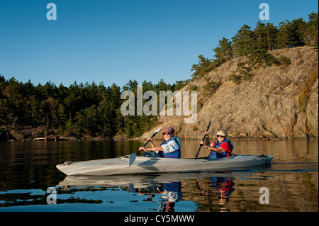 Two women kayak off of Shaw Island in the San Juan Islands of Puget Sound in the Pacific Northwest of Washington State. Stock Photo