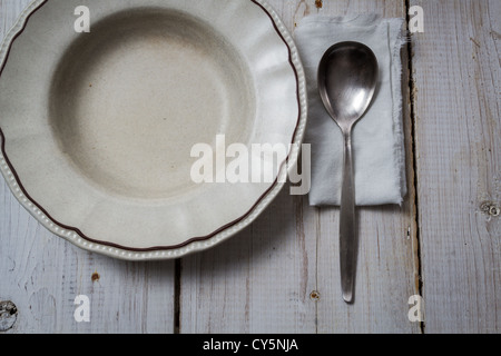 Old empty plate and spoon on wooden table Stock Photo