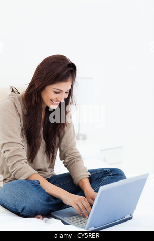 Woman smiling as she uses her laptop on the couch, side view Stock ...