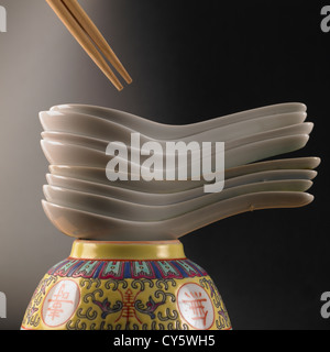 Chinese soup spoons stacked on an upturned ornate soup bowl with wooden chopsticks Stock Photo