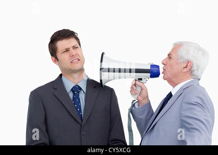 Close up of mature businessman with megaphone yelling at colleague Stock Photo