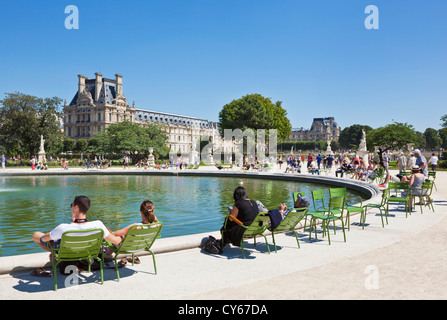 Tourists enjoying the sunshine in deckchairs around a lake in the Tuileries Gardens  near the Louvre Gallery Paris France EU Stock Photo